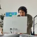 Focused view of HP All-in-One 24-cr0247d Core i5 PC with user wearing headset engaged in online activity at home.