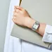 Wrist view of Casio AQ-230A-7DMQ Watch with silver band, white dial, and small digital display while holding a book.
