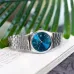 Casio MTP-B145D-2A2VDF Watch with silver band and blue dial placed on open book with green leaves background.