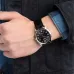 Wrist view of Casio MTP-V001L-1BUDF Watch with silver case, black dial, and white numerals worn with plaid shirt.