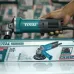 Handheld side view of the TOTAL TG10710076 100mm 710w Angle Grinder held above its product box