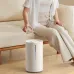 Person refilling Xiaomi Smart Humidifier 2 on wooden floor by pouring water into its cylindrical design.