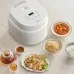 Kitchen tabletop view of the Panasonic SR‑DL184 1.8L Rice Cooker placed beside cooked dishes and ingredients.