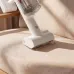 Handheld view of Xiaomi Mijia Vacuum Cleaner 4 cleaning beige sofa cushion with transparent dust container.