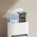 Upright view of Xiaomi X20 Robot Vacuum Cleaner beside modern water dispenser in clean home setting.