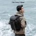 Medium shot of a man wearing the black K&F Concept KF13.128V4 backpack with a tripod secured to the side.