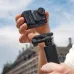Close-up of Insta360 GO Ultra camera and grip mount held outdoors with urban building and cloudy sky background.