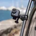 Mounted view of Insta360 GO Ultra camera clamped to bicycle frame near waterfront with blurred boats in background.