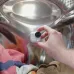 Close-up of Insta360 GO Ultra camera positioned inside washing machine drum with colorful clothes.