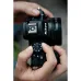 Close-up of hands adjusting the mode dial on the top of the black Nikon Z50 II mirrorless camera.