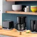 Kitchen view of Braun Breakfast1 KF1100 Coffee Maker beside Braun toaster and kettle on wooden countertop.