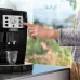 Front view of DeLonghi ECAM22-110 Magnifica S Coffee Machine with hand pressing control panel button to brew coffee.