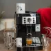 Lifestyle view of DeLonghi ECAM22-110 Magnifica S Coffee Machine brewing espresso on countertop with mugs and cups nearby.