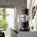 DeLonghi KG521 Dedica coffee grinder with coffee beans and grounds container in a modern kitchen.