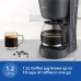 Countertop view of Philips HD7430/90 Coffee Maker with 1.2L glass jug brewing hot coffee beside mug and beans.