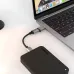 Close-up of a black Toshiba portable hard drive plugged into a MacBook laptop via a dongle.