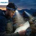 Outdoor view of Philips SFL3342RH/56 Headlamp worn by hiker illuminating map during twilight mountain trek.