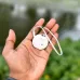 Handheld view of XO LP01 Anti-Lost Device Smart Tracker showing round body with strap against outdoor blurred background