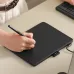 Huion Inspiroy Frego M Graphic Tablet shown in use with a stylus on the drawing surface connected to a computer.
