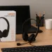 Desk setup view of the Meetion MT‑HP003 Wired Headphone placed beside keyboard and accessories on a wooden workspace.