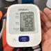 Handheld view of Omron HEM-7121 BP Monitor showing SYS 125, DIA 89, and pulse 82 readings on screen.