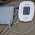 Close-up of Omron HEM-7121J BP Monitor with IntelliSense cuff and display showing test values for SYS, DIA, and pulse.