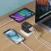 The black BWOO BO-UC08 travel adapter charges a phone, tablet, and laptop via multiple cables on a wooden desk.