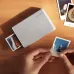 Xiaomi Portable Photo Printer 1S printing a photo while being used on a wooden desk.