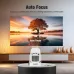 Magcubic HY310 Mini Android Projector sits on a table projecting a vivid sunset landscape onto a large wall display.