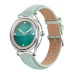A silver smartwatch with a mint green leather strap displays a green watch face with jeweled markers.