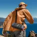 A man in an outdoor setting carries the Soundcore Boom 3i speaker with its shoulder strap, showcasing its portability.