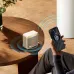 Lifestyle view of BWOO BO-BS96 Portable Bluetooth Speaker placed on table wirelessly charging smartphone in modern indoor setting