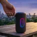 Lifestyle outdoor view of Unikyy S7 Portable Bluetooth Speaker placed on wooden surface with LED lights glowing while hand hovers above