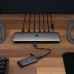 A front view of a EX100U external SSD connected to a multi-port hub on a wooden desk between two speakers.