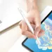 Hand using white stylus pen on tablet screen for drawing with laptop visible in background