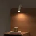 Bedside view of Xiaomi Flexible Rechargeable Lamp mounted on headboard casting warm light over book and candle.
