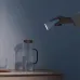 Lifestyle view of Xiaomi Flexible Rechargeable Lamp used as handheld flashlight illuminating pitcher on wooden table.
