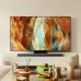 The Samsung 65QN70F QLED TV sits on a low stand with a soundbar, displaying abstract, colorful canyon art.