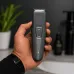 Philips BT1243-18 beard trimmer held in hand, showing textured grip, precision blades, and green LED indicator.