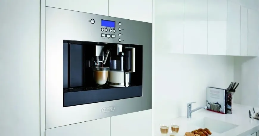 Front view of a built-in stainless steel DeLonghi PrimaDonna EABI 6600 coffee machine installed neatly within modern kitchen white cabinetry
