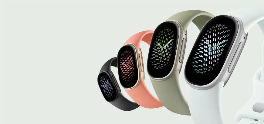Four Google Fitbit Edge in black, coral, olive green, and mint, lined up in a row with colorful watch faces