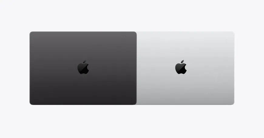 Overhead view comparing two New MacBook Pro lids side-by-side in dark space black and light silver finishes with black Apple logos.