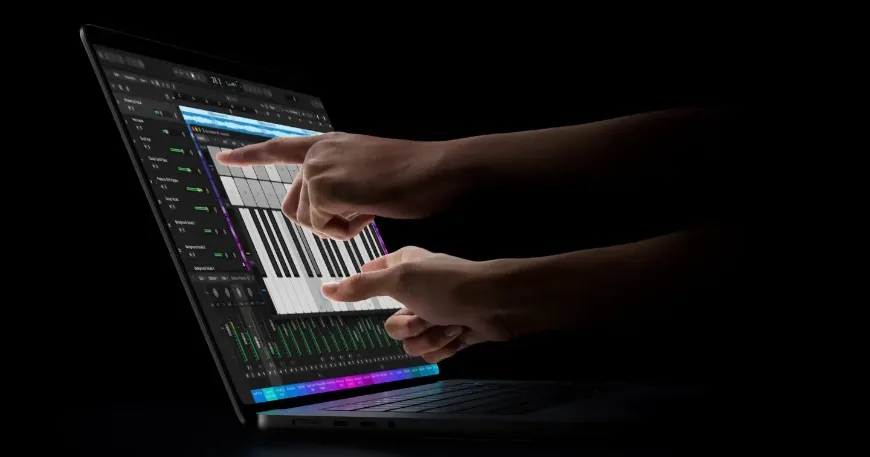 Side perspective of hands using multi-touch gestures on a touchscreen macbook pro displaying music production software against a dark background.